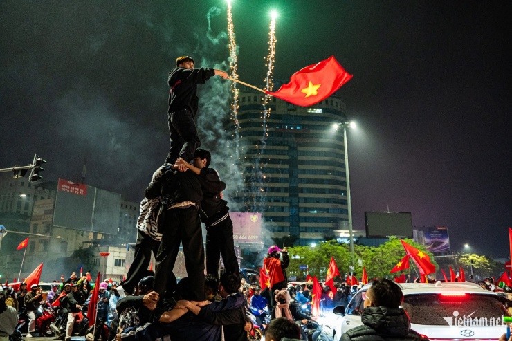 Tại ngã tư Giải Phóng - Đại Cồ Việt, một nhóm thanh niên xếp hình tháp người, vẫy cao lá cờ trong sự thích thú của những người xung quanh.