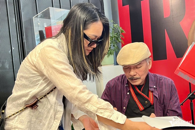 Con gái nhạc sĩ Trần Tiến - chị Thảo Nguyên - hỗ trợ cha ký tặng sách cho độc giả.&nbsp;