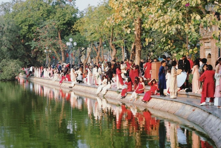 Từ sáng đến chiều, quanh các địa điểm quen thuộc như Tháp Rùa, cầu Thê Húc, đền Ngọc Sơn hay phố Đinh Tiên Hoàng, hình ảnh những cô gái trẻ diện áo dài đủ màu sắc xuất hiện liên tục. Áo dài đỏ, hồng, trắng hoặc họa tiết hoa được ưu tiên lựa chọn, gợi không khí Tết trong những ngày cuối năm.