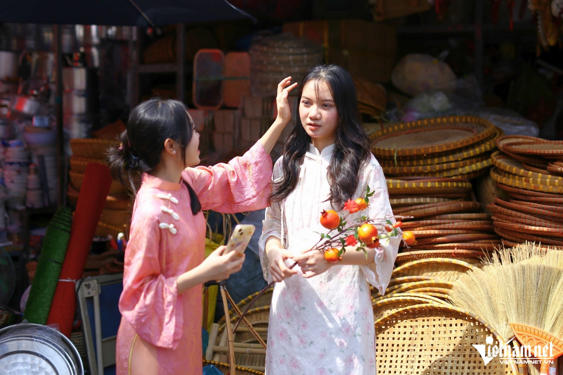 Từ sáng sớm, từng nhóm bạn trẻ đã có mặt, xúng xính trong tà áo dài truyền thống hoặc cách tân, tay cầm giỏ mây, hoa tươi, hòa mình vào dòng người mua bán rộn ràng. Các “nàng thơ” dạo bước chụp ảnh ở khu chợ, tạo nên bức tranh nhộn nhịp mùa xuân.