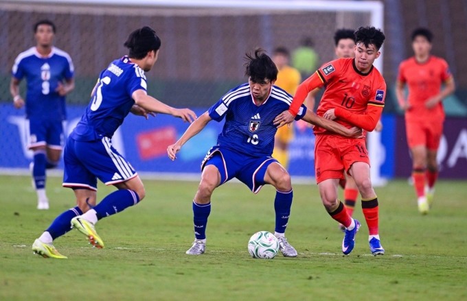 Wang Yudong (số 10, cam, Trung Quốc) tranh bóng với Sato (số 10, xanh, Nhật Bản) trên sân Prince Abdullah al-Faisal. Ảnh: AFC