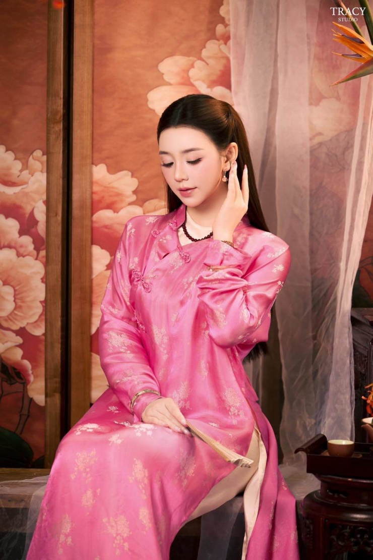 Thiết kế cổ cao truyền thống kết hợp khuy cài hoa văn nhỏ, giữ nguyên nét cổ điển nhưng được cách tân nhẹ ở phần tay áo dài hơi bồng bềnh ở vai và tà áo xẻ cao vừa phải. Phần tà áo dài thướt tha, layer lụa trắng mỏng bên trong tăng chiều sâu cho lớp vải ngoài, đồng thời đảm bảo sự kín đáo và tôn lên đường nét cơ thể thon gọn của Quỳnh Kool.