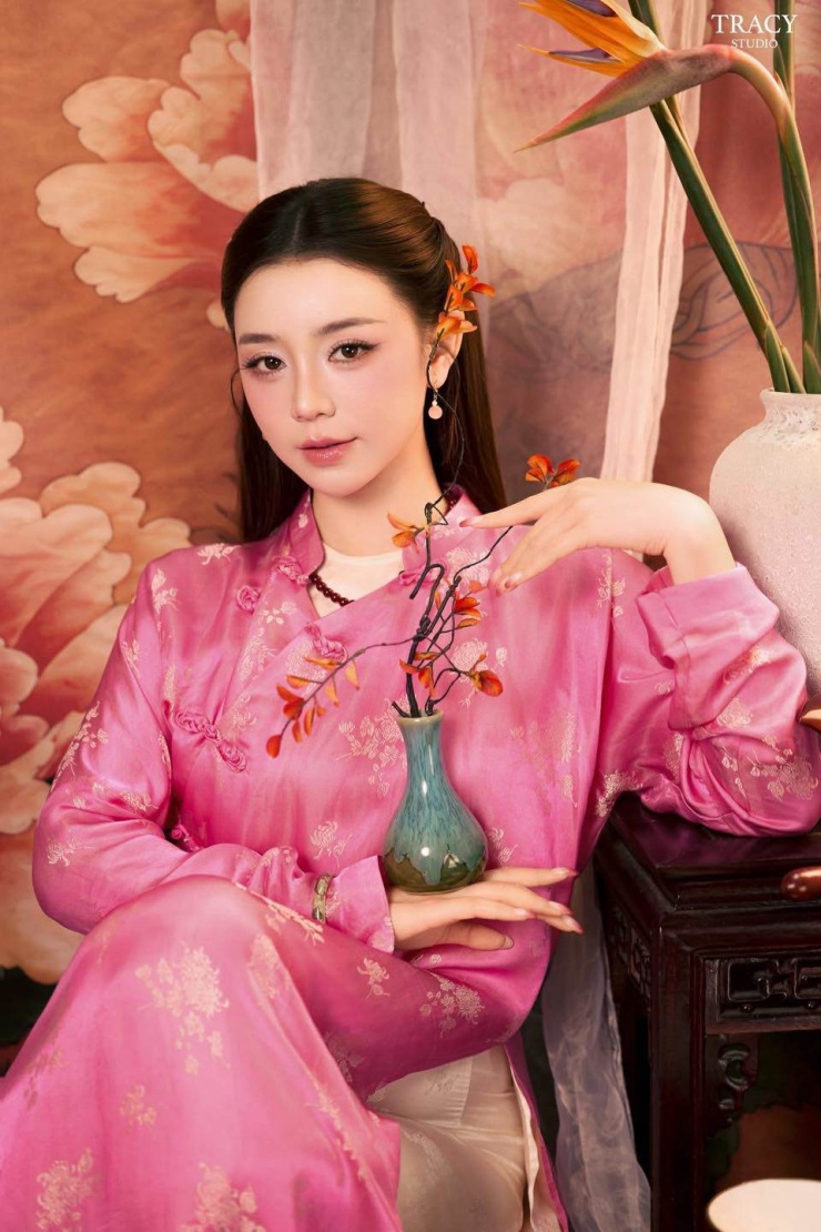 Quỳnh Kool chọn áo dài màu hồng phấn làm chủ đạo, chất liệu lụa mỏng nhẹ, bóng mịn, tạo cảm giác mềm mại và bay bổng. Họa tiết hoa mai hoa đào thêu nổi tinh xảo rải đều trên nền vải, mang biểu tượng thanh lịch và nữ tính đặc trưng của áo dài Việt Nam.