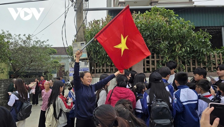 Người dân vui mừng cầm cờ Tổ quốc vẫy, chào đón sự trở về của thủ thành Cao Văn Bình. (Ảnh: Bá Thăng).
