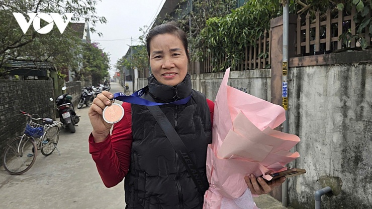 Chị Nguyễn Thị Hường, mẹ thủ thành Cao Văn Bình cùng tấm huy chương đồng của U23 Việt Nam. (Ảnh: Bá Thăng).