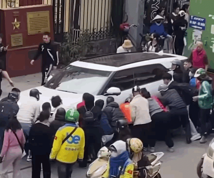 Nhiều người tập trung để tìm cách nhấc một bên chiếc ô tô lên để cứu nạn nhân. Ảnh: Giao thông văn minh