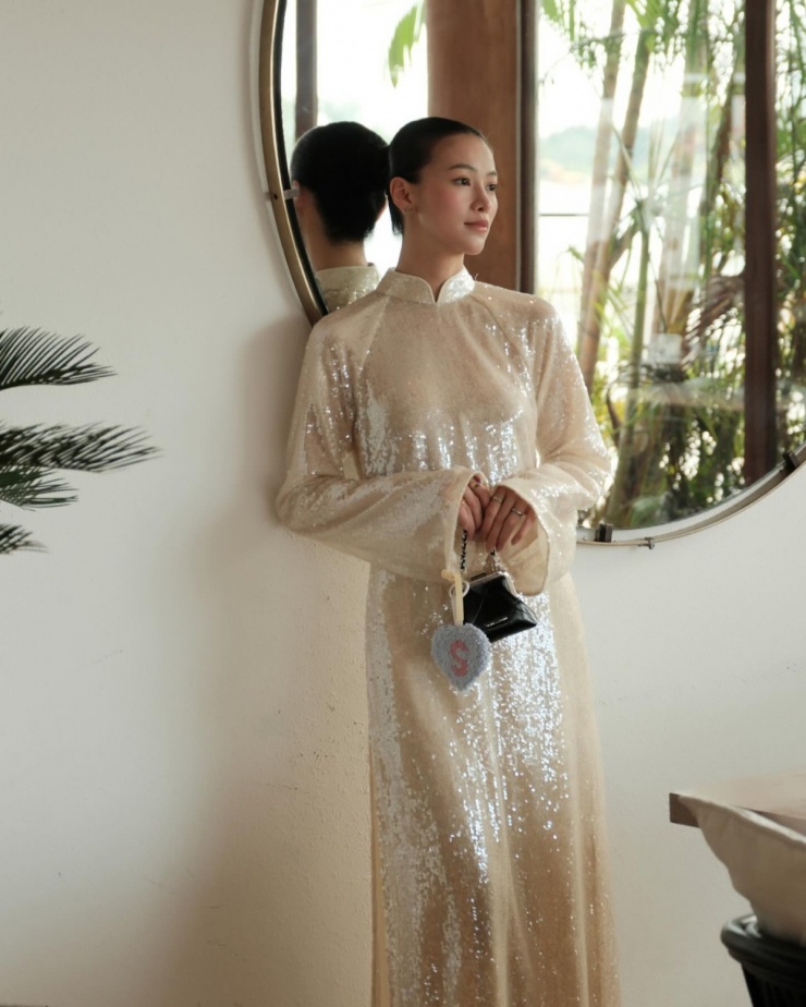 Phương Khánh chọn áo dài kim sa lấp lánh, phù hợp với không khí rộn ràng ngày Tết. Chất liệu bắt sáng giúp thiết kế trở nên nổi bật dù phom dáng đơn giản tối đa.