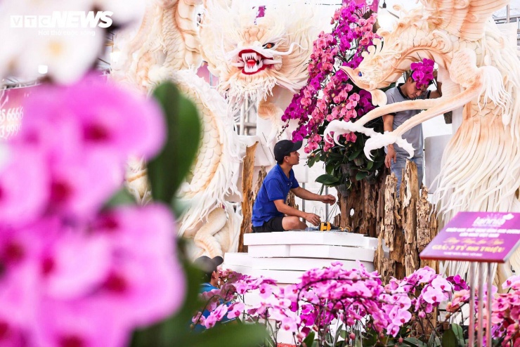 Đáng chú ý, một số cửa hàng còn thiết kế các tác phẩm lan nghệ thuật quy mô lớn, kết hợp hoa lan với lũa và các vật liệu trang trí. Một tác phẩm mang tên “Long phụng sum vầy” đang được nhóm thợ hoàn thiện, đòi hỏi nhiều công đoạn từ tạo khung, cắm hoa đến chỉnh sửa chi tiết.