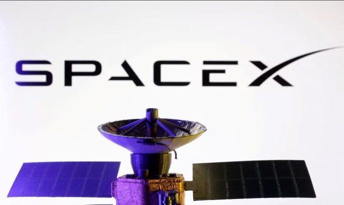 Logo SpaceX đặt bên cạnh mô hình một vệ tinh thu nhỏ. Ảnh: Reuters