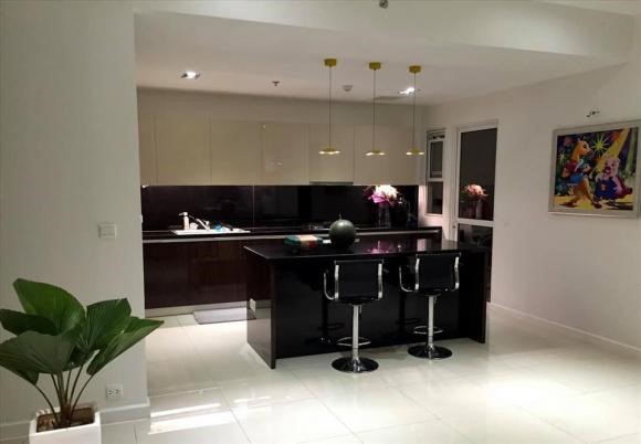 Khu vực bếp đầy đủ các vật dụng cần thiết như: bếp gas, máy rửa chén tự động, máy lọc nước, dàn tủ bếp với thiết kế gỗ bóng để phản chiếu ánh sáng của view chung cư.