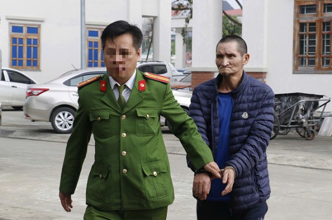 Nghi can Xìa (góc phải) bị cảnh sát dẫn giải về trụ sở. Ảnh: Công an cung cấp