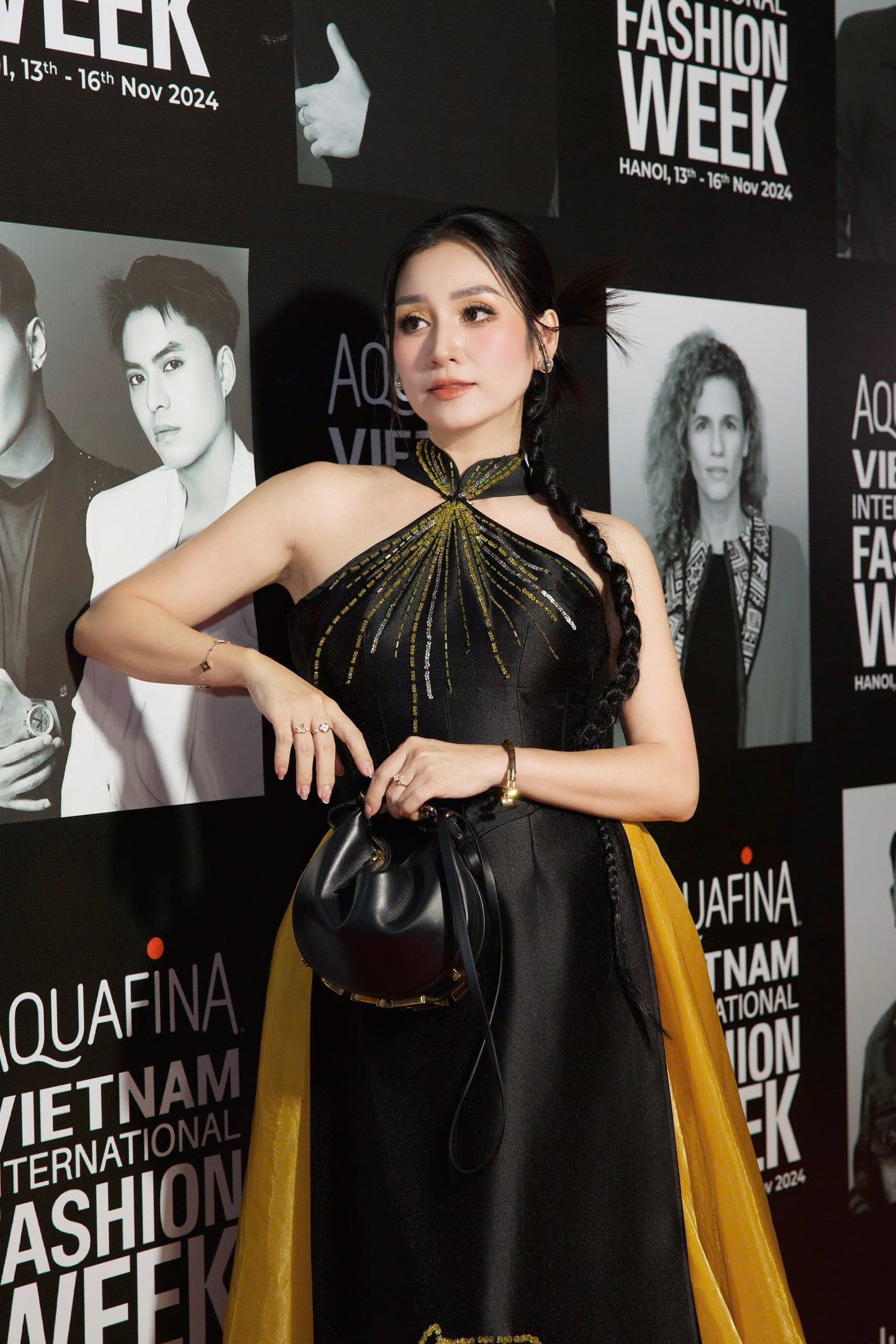 MC Thanh Mai gây ấn tượng khi lựa chọn chiếc áo dài cách tân đầy ấn tượng với gam màu đen chủ đạo kết hợp cùng tà áo vàng rực rỡ, tạo nên sự tương phản hài hòa và cuốn hút. Thiết kế áo dài này không chỉ giữ được nét truyền thống đặc trưng của trang phục Việt Nam mà còn mang phong cách hiện đại với phần cổ yếm độc đáo, điểm nhấn họa tiết ánh kim tinh tế trải dài trên thân áo, thể hiện sự sang trọng và thời thượng.