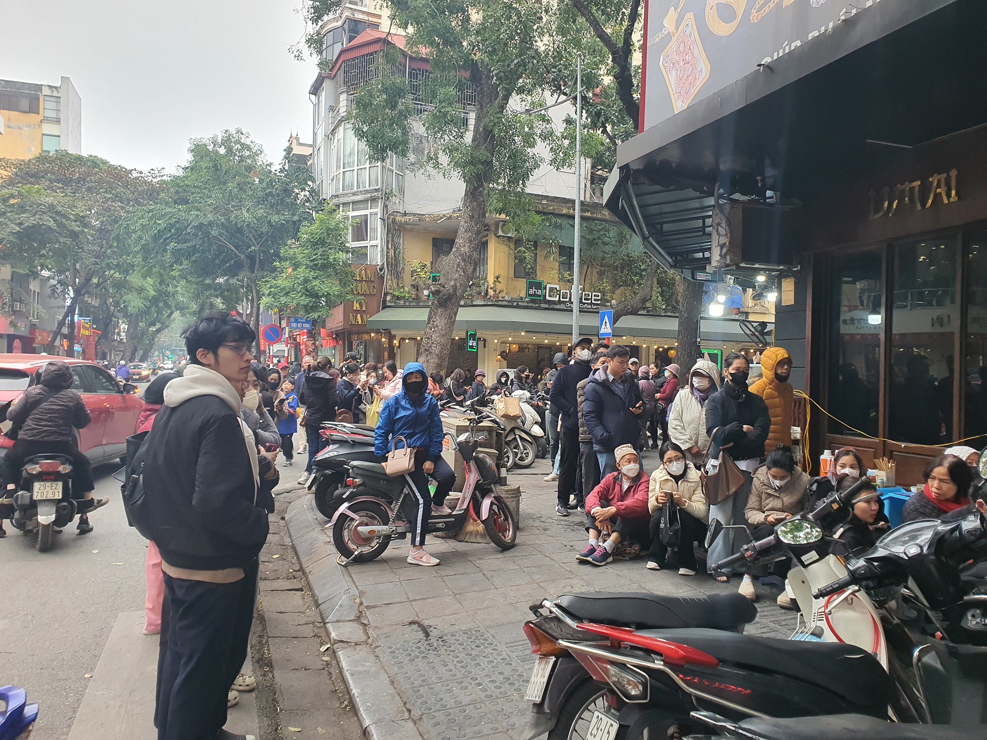 Nhiều người chờ quá lâu phải kê dép xuống vỉa hè ngồi cho đỡ mỏi chân.