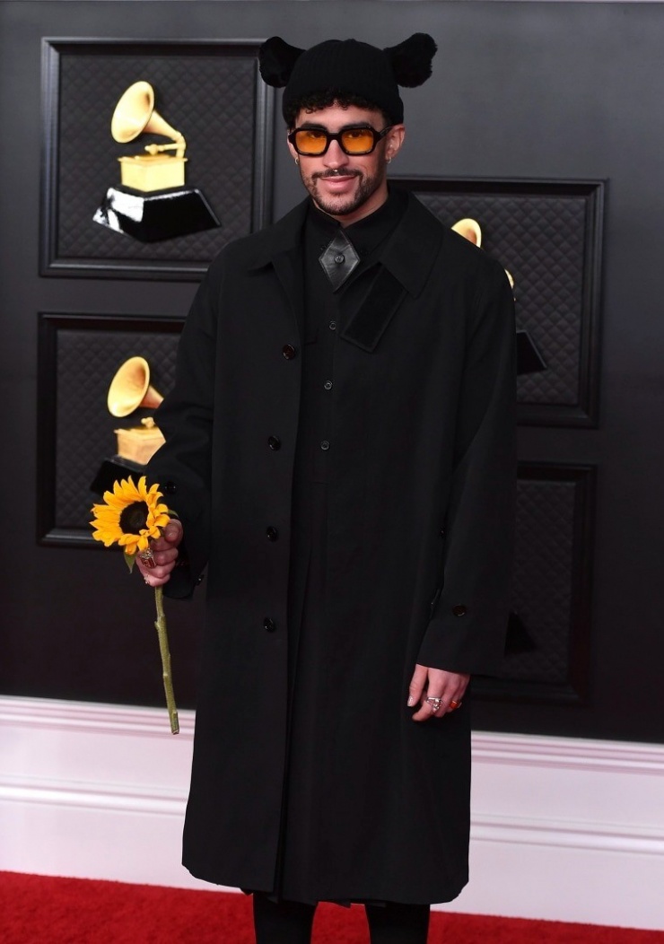 Ở Grammy 2021, Bad Bunny mang đến phong cách gothic bằng cả bộ màu đen. Phụ kiện là cành hoa hướng dương tạo điểm nhấn màu sắc thú vị cho tổng thể. Ảnh: GQ