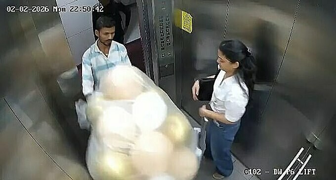 Nhân viên giao hàng mang chùm bóng bay vào trong thang máy. Ảnh: X