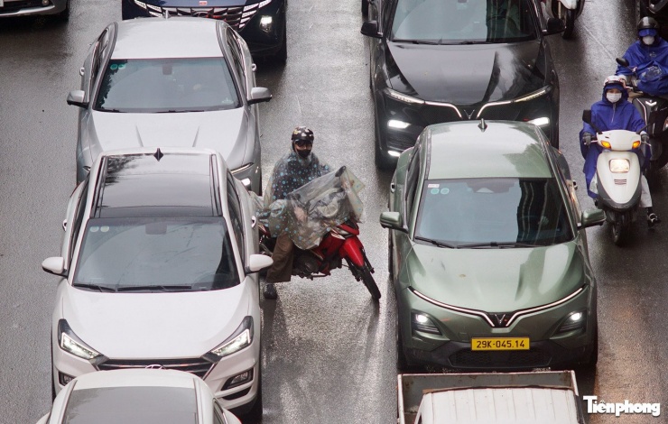 Một tài xế xe máy len lỏi vào giữa hàng xe ô tô để di chuyển qua khu vực tắc đường.