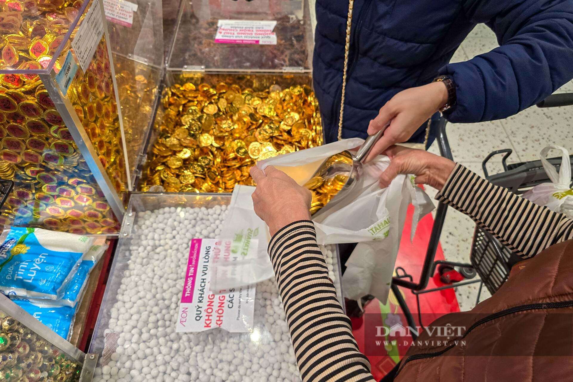 Tại đây, hàng trăm khay bánh, kẹo dẻo, thạch rau câu, sô-cô-la đồng tiền... đủ màu sắc sặc sỡ được đổ đống tạo nên một "ma trận" ngọt ngào vô cùng bắt mắt. Điểm cộng lớn nhất của loại mặt hàng này là mức giá "siêu mềm", chỉ dao động từ 40.000 – 90.000 đồng/kg tùy loại.&nbsp;Tay nhanh thoăn thoắt xúc đầy một túi lớn gồm đủ loại kẹo dẻo và thạch, bà Nguyễn Thị Lan (Thanh Xuân) chia sẻ: "Tết nhất chủ yếu mua cho trẻ con đến chơi hoặc bày khay mứt cho đẹp. Kinh tế năm nay khó khăn, mua bánh hộp nhập khẩu thì tốn kém quá, lại được ít. Cứ mua hàng cân thế này vừa rẻ, vừa chọn được nhiều vị, bày ra khay trông rất đầy đặn và rực rỡ".