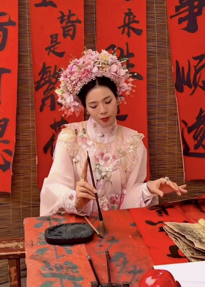 Lệ Quyên cài trâm hoa, tạo dáng đang viết thư pháp, chụp hình tại làng Tuyền Phố.