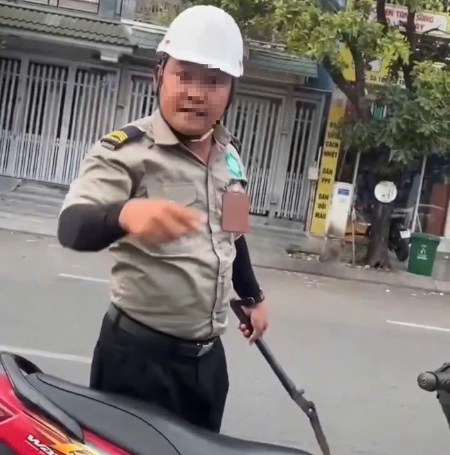 Một người mặc đồng phục bảo vệ cầm hung khí.