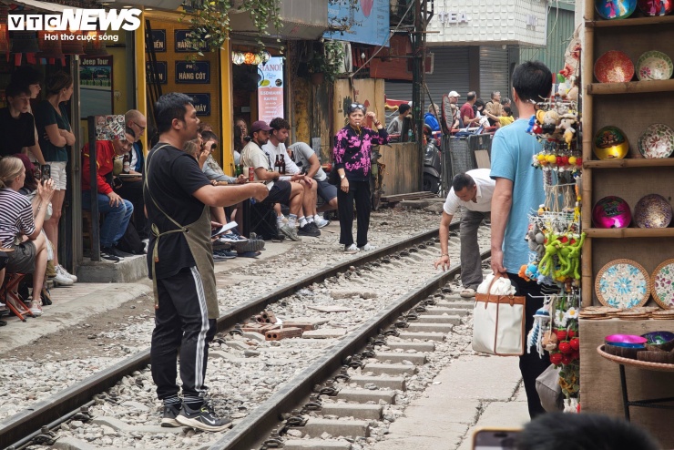Trước giờ tàu chạy khoảng 10 phút, các chủ quán đồng loạt thổi còi, hô lớn yêu cầu du khách di chuyển vào trong. Nhân viên nhanh chóng thu gọn bàn ghế, bê vào sát tường, dọn sạch phần ray. Du khách được hướng dẫn đứng nép sát hai bên, nhiều người áp lưng vào tường nhà.