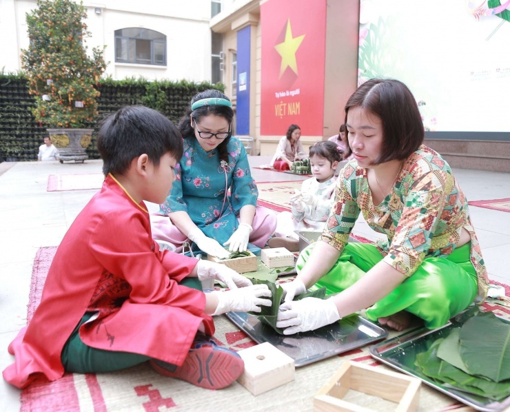 Cô Minh Thúy (ở giữa) cùng gói bánh chưng với phụ huynh, học sinh và giáo viên trong trường trong ngày hội Xuân. Ảnh: Tào Nga