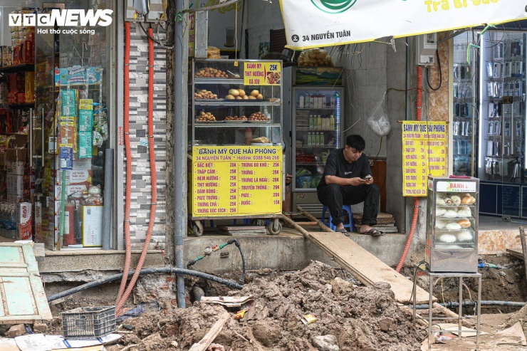 Không chỉ việc đi lại bị ảnh hưởng, hoạt động kinh doanh của các hộ dân dọc tuyến cũng gặp khó. Bùn đất bám vào giày dép khách ra vào khiến nhiều cửa hàng phải lau dọn liên tục. Có nơi khách ngại dừng xe do không còn khoảng trống trước cửa.