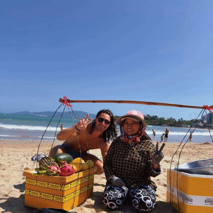 Anh Local Lou hào hứng chụp ảnh cùng cô bán hoa quả bên bờ biển Nha Trang, Khánh Hòa. Ảnh: NVCC