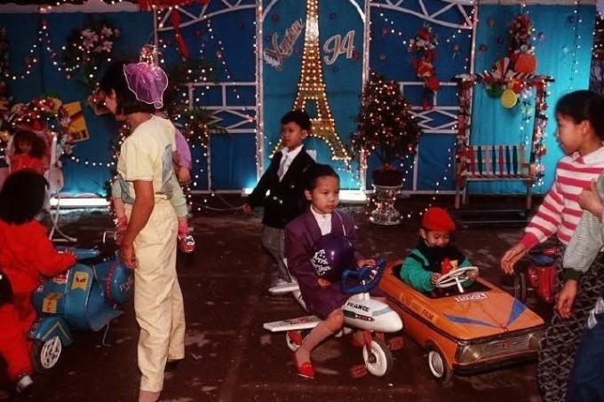 Một khu vui chơi với các phương tiện như ôtô, xe máy, máy bay thu nhỏ. Trẻ em thành phố mặc trang phục rực rỡ, gọn gàng trong ngày Tết.