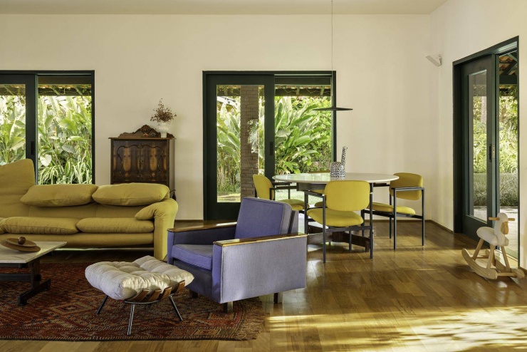 Khu vực tiếp khách phụ với bộ sofa màu vàng mù tạt nổi bật trên nền sàn gỗ. Nguồn: Archdaily