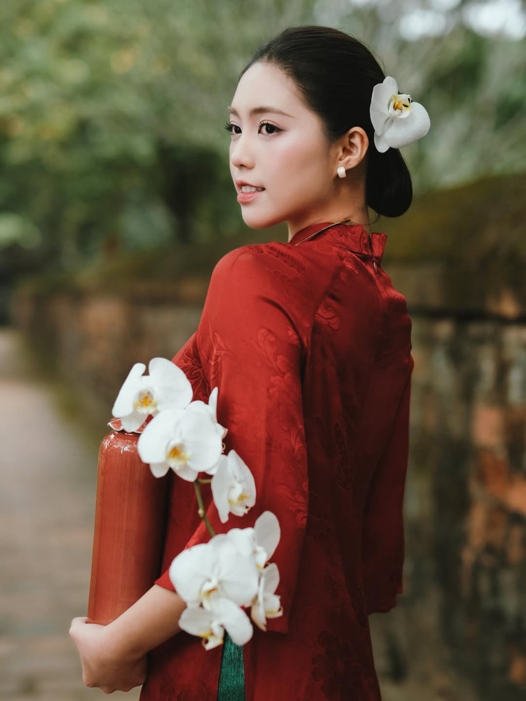 Á hậu Châu Anh kiều diễm trong trang phục áo dài màu đỏ nổi bật. Người đẹp búi tóc, trang điểm nhẹ nhàng, khoe vẻ thanh lịch.