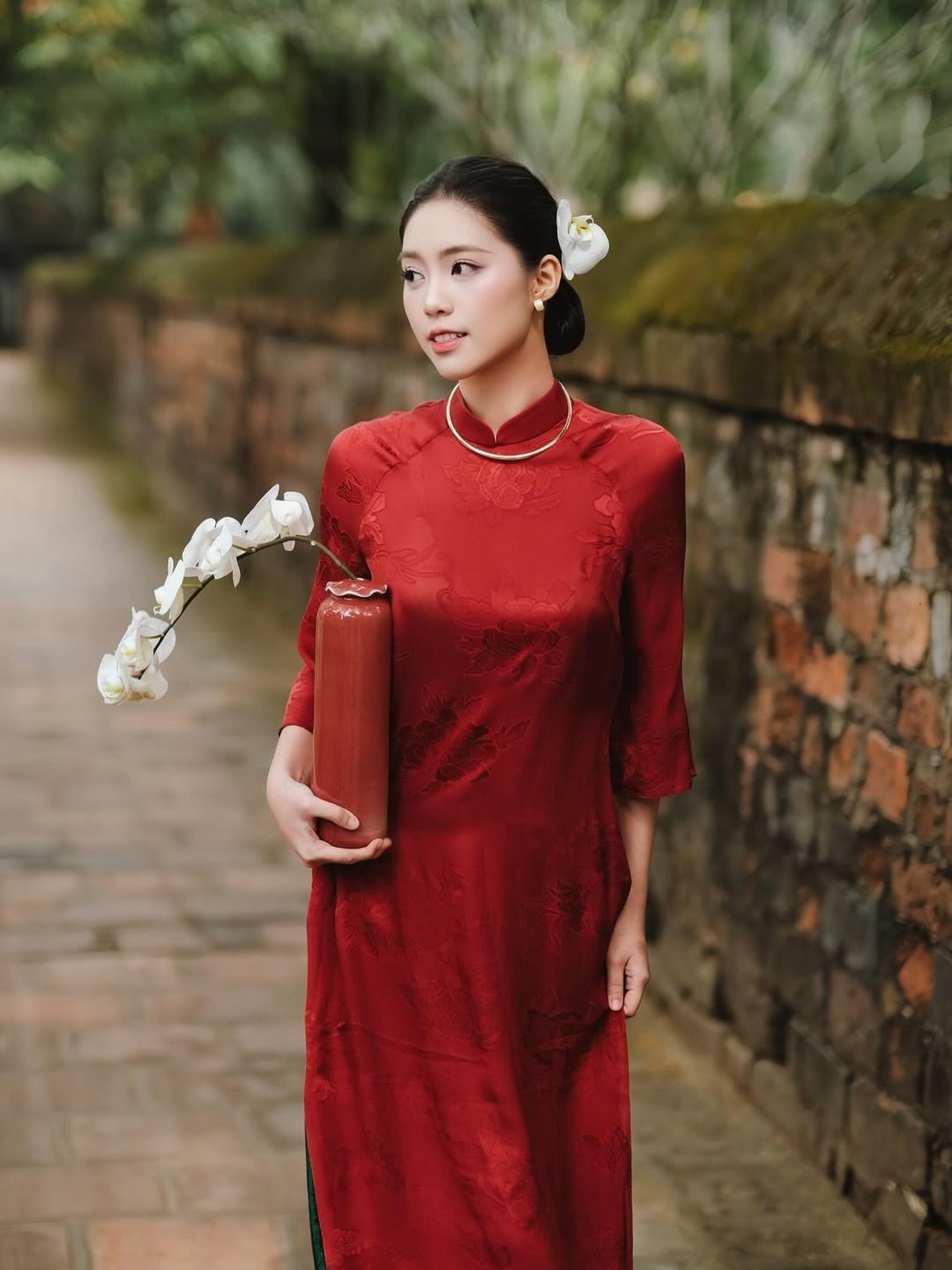 Á hậu Châu Anh kiều diễm trong trang phục áo dài màu đỏ nổi bật. Người đẹp búi tóc, trang điểm nhẹ nhàng, khoe vẻ thanh lịch.