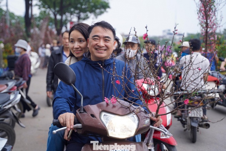 Phấn khởi mua được cành đào ưng ý, anh Hiếu (phường Cầu Giấy) chia sẻ: “Tôi mua cành này với giá 100.000 đồng. Hôm nay mới được nghỉ làm nên tranh thủ đưa vợ đi sắm sửa”.