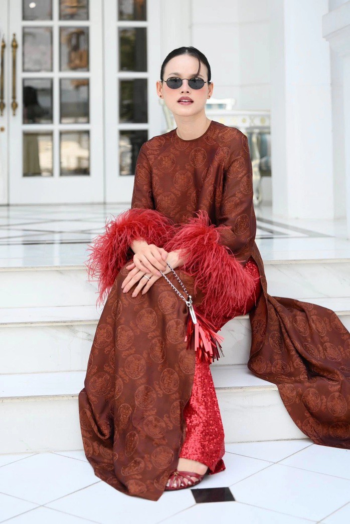 Tuyết Lan hưởng ứng xu hướng áo dài đính lông vũ, phối quần sequin trong thiết kế của Adrian Anh Tuấn. Cô dùng cặp kính tròn để tạo vẻ hoài cổ.
