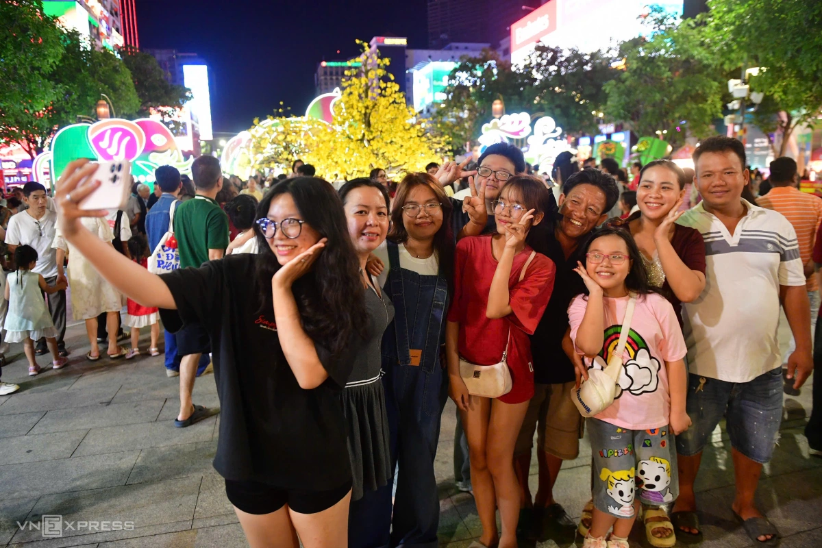 Gia đình bà Nguyễn Thị Mai Liên từ xã Bà Điểm (huyện Hóc Môn cũ) đến phố đi bộ chơi. "Năm nào dịp cuối năm, cả gia đình cũng đi chơi thong thả. Năm nay đường hoa thấy đẹp hơn mọi năm", bà Liên nói. Ảnh:&nbsp;Thanh Tùng