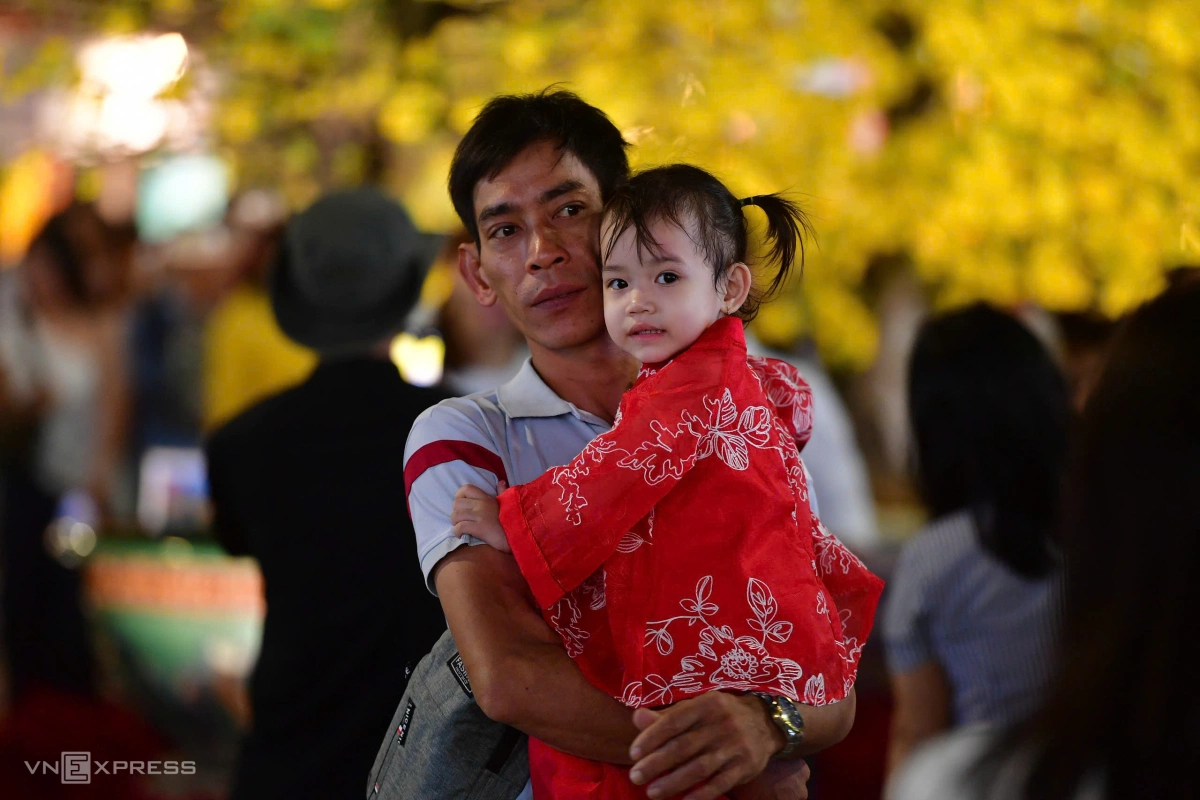 "Lần đầu hai cha con đi chơi lễ đêm giao thừa", anh Nguyễn Thành Lực, 36 tuổi, Thủ Đức ẵm con đi chơi ở đường hoa nói. Ảnh:&nbsp;Thanh Tùng