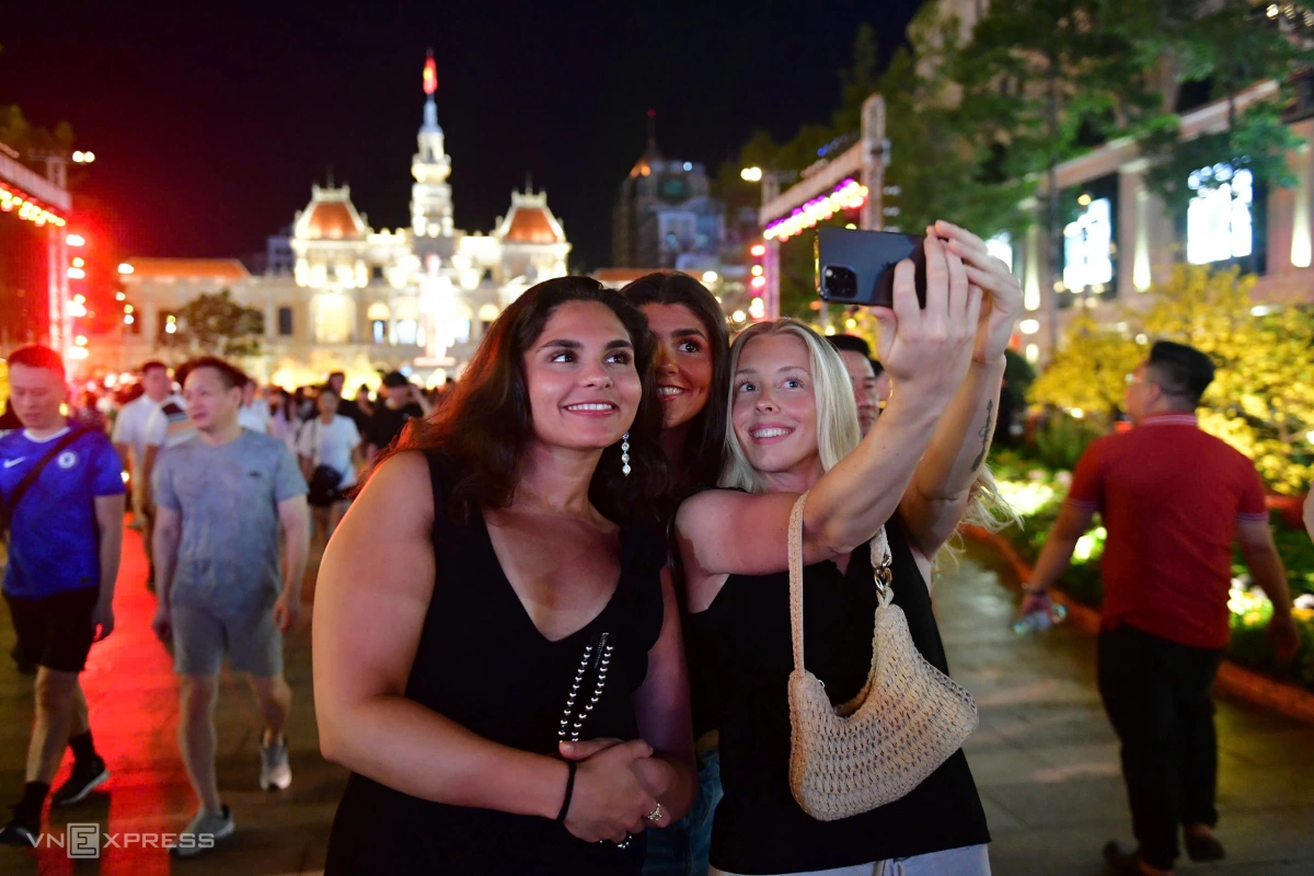 Nhóm du khách nước ngoài chụp hình lưu niệm trên đường hoa Nguyễn Huệ. Ảnh:&nbsp;Thanh Tùng