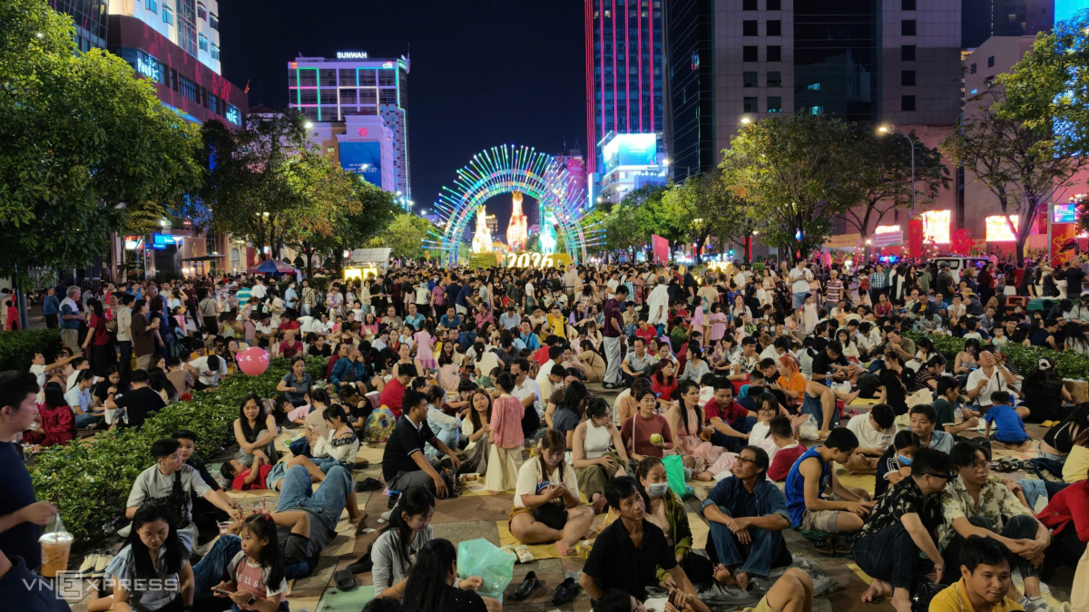 Người dân ngồi chờ trước đường hoa Nguyễn Huệ đoạn gần công viên Bến Bạch Đằng để chờ xem pháo hoa. Ảnh:&nbsp;Đình Văn