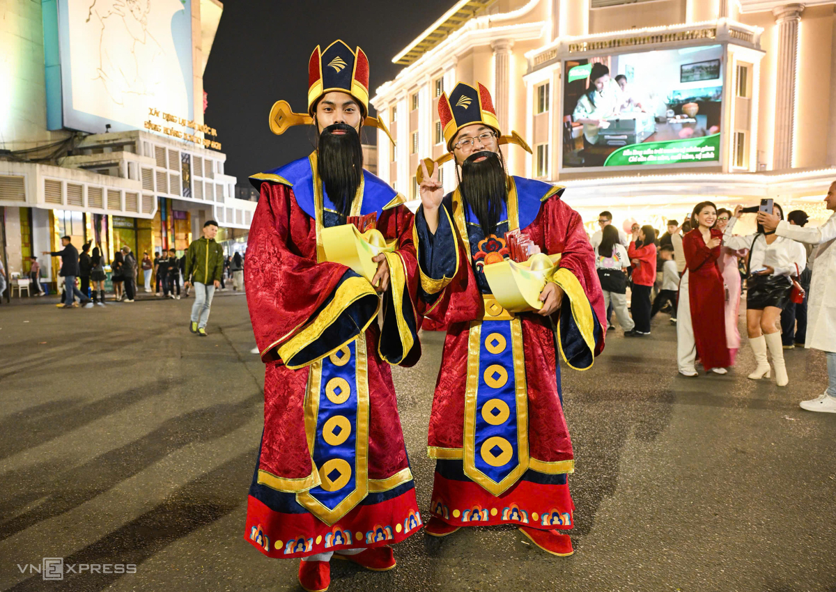 Trên phố, hai người dân cosplay Thần Tài phát bao lì xì cho người đi đón giao thừa. Ảnh: Giang Huy