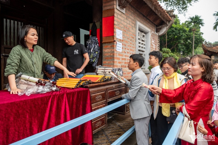 Năm nay, hoạt động xin chữ tại Văn Miếu – Quốc Tử Giám được tổ chức rất trật tự. Người dân xếp hàng mua giấy và nhận số thứ tự, sau đó kiên nhẫn chờ đến lượt để xin chữ thư pháp từ các ông đồ.