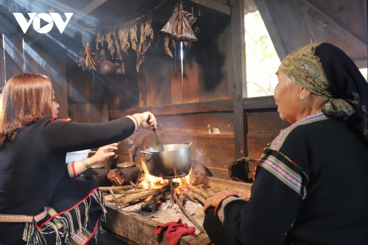 Bếp củi đỏ lửa trong gian bếp nhà dài, âm thanh xào nấu vang lên, mùi thức ăn lan tỏa khắp không gian.