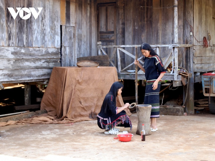 Ngoài sân, hai chị em H Nin Êban và H Tuyết Êban cùng nhau giã đu đủ xanh