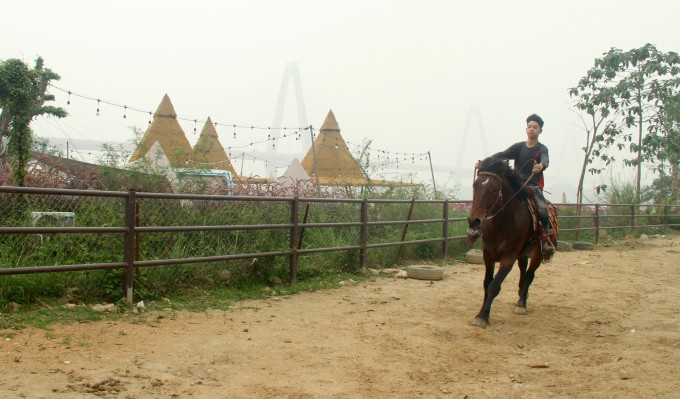 Hoàng Tuấn Tú cưỡi chú ngựa A Phạn ở dưới bãi sông, gần cầu Nhật Tân, Hà Nội hôm 6/2. Ảnh: Phan Dương
