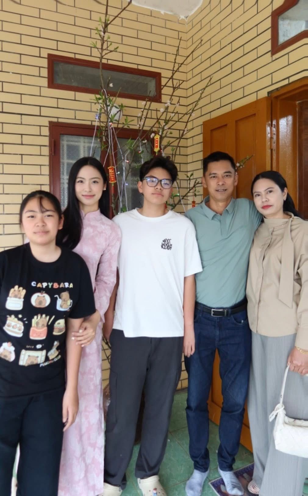 Á hậu Vân Nhi cùng bố mẹ và các em đi chúc Tết họ hàng vào ngày Mùng 2. Người đẹp mặc áo dài tông màu hồng nhạt nền nã.