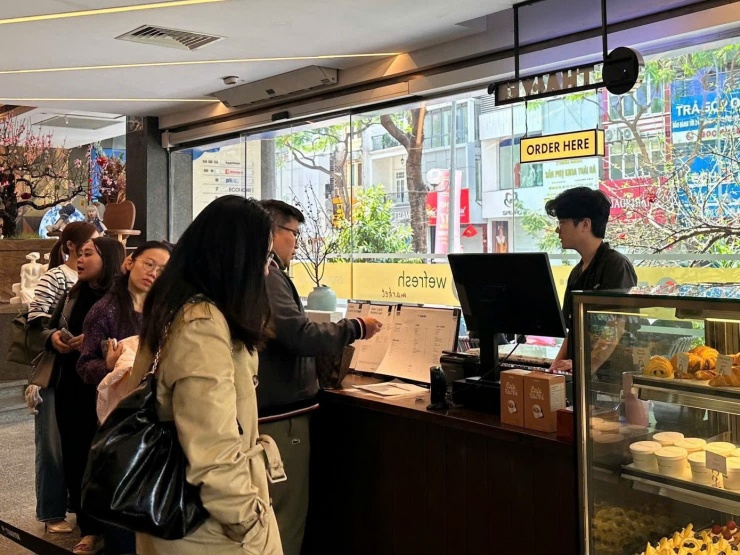 Khách xếp hàng chờ tới lượt gọi đồ tại quán cafe. Trong dịp cao điểm Tết Nguyên đán, rất nhiều quán cafe tại khu vực trung tâm Thủ đô đã mở cửa trở lại. Một số nơi dành tặng lì xì may mắn, voucher giảm giá cho khách hàng.