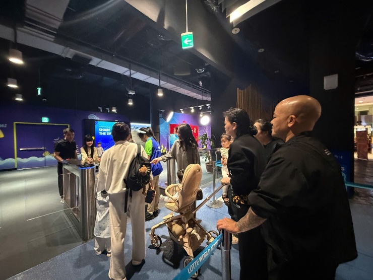 Các gia đình cùng em nhỏ xếp hàng mua vé, chờ vào khu vui chơi.