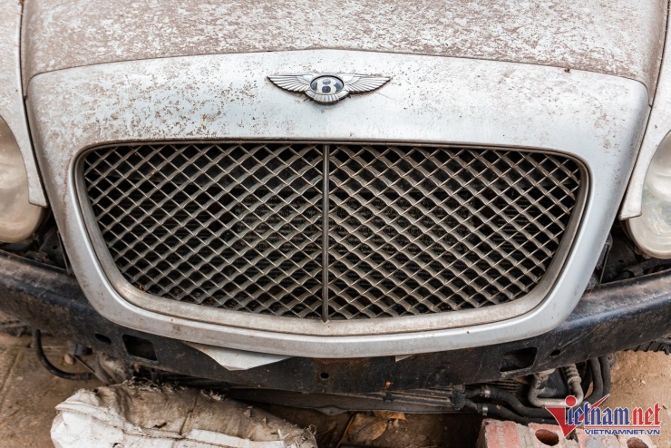 Mặt ca-lăng mạ crôm đã hoen ố nghiêm trọng, không còn vẻ sáng bóng vốn có của chiếc Bentley thường thấy. Logo Bentley phía trên còn nguyên, chưa bị mất sau thời gian dài chiếc xe phủ bụi.