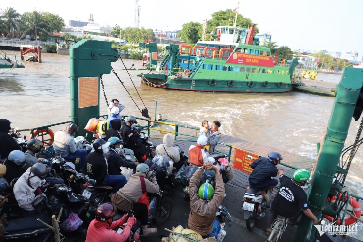Dưới lòng sông, các chuyến phà hoạt động hết công suất, liên tục cập bến để giải tỏa "biển người" đang kiên nhẫn xếp hàng dưới nắng.