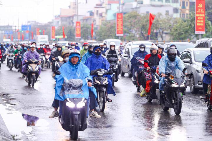 Trong cơn mưa phùn kéo dài, việc đi lại của người dân càng thêm vất vả, nhiều phương tiện phải di chuyển chậm để đảm bảo an toàn.