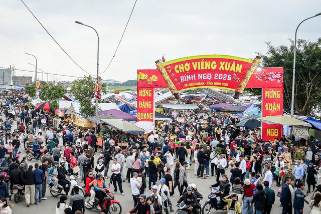 Cổng chợ rực rỡ băng rôn nổi bật giữa dòng người đông đúc. Những bước chân hối hả, những nụ cười rạng rỡ làm nên nhịp điệu rộn ràng của ngày hội.