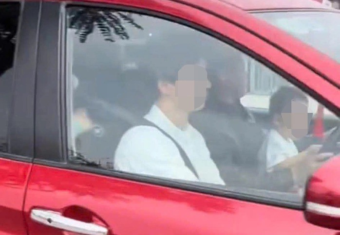 Nam tài xế ôm một trẻ nhỏ trong lòng khi ngồi lái ô tô, tay đứa trẻ cầm vào vô lăng. Ảnh cắt từ clip